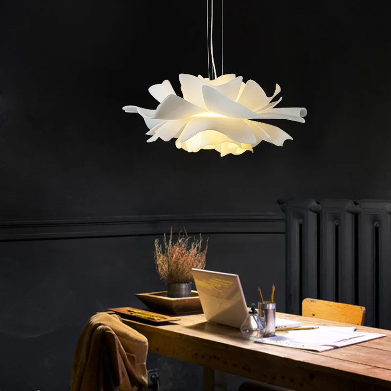 Floral pendant light above a wooden desk with a laptop and stationery items.