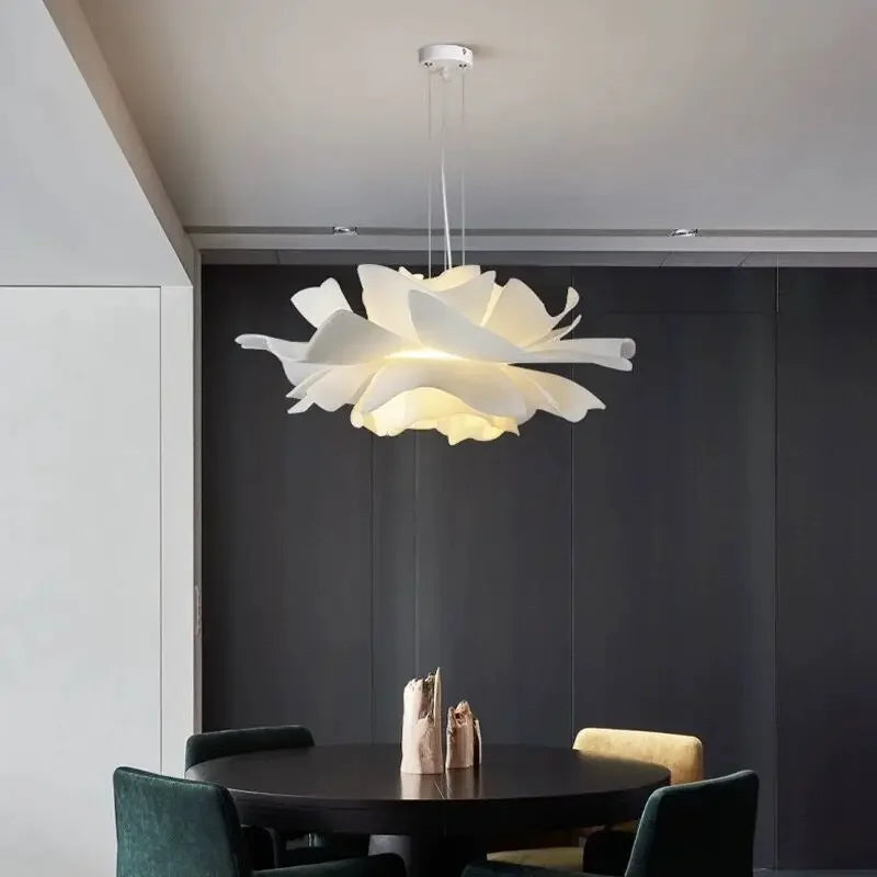 Modern chandelier hanging above a dining table in a room with a dark wall.