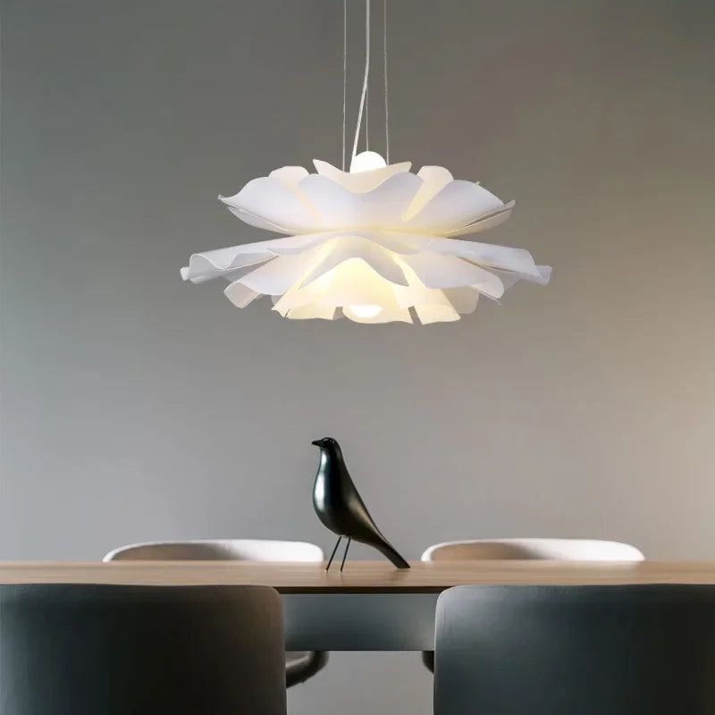 Modern pendant light fixture hanging above a table with a bird sculpture.