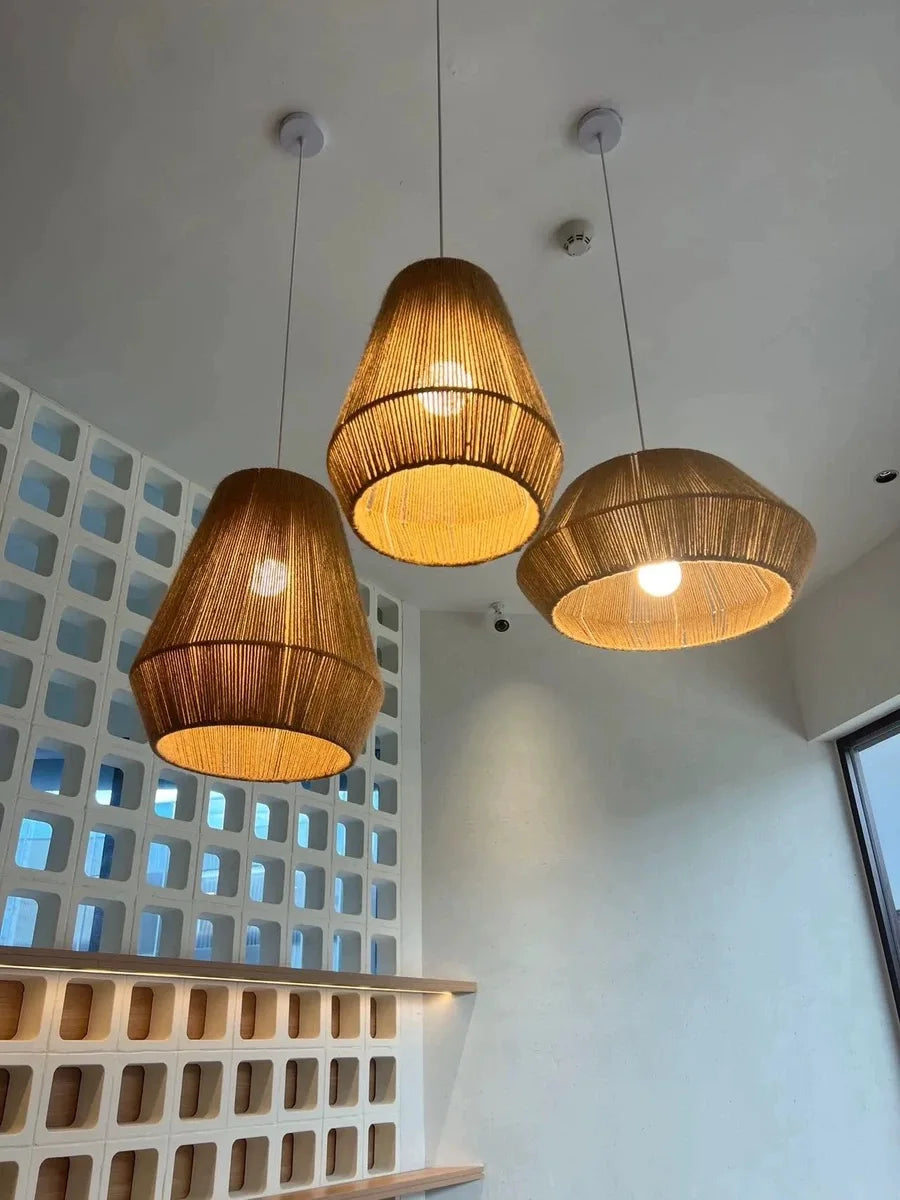 Three wooden pendant lights hanging from the ceiling with a light blue wall and geometric patterned wall in the background.