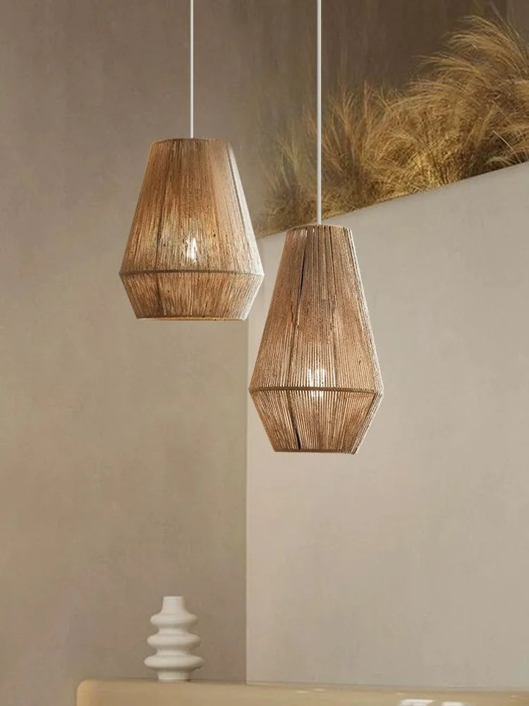 Two wooden pendant lights hanging against a neutral wall with a decorative plant in the background.