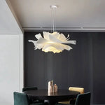 Modern chandelier hanging above a dining table in a room with a dark wall.