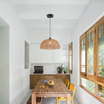 Modern kitchen with wooden dining table, yellow chairs, and a wicker pendant light.