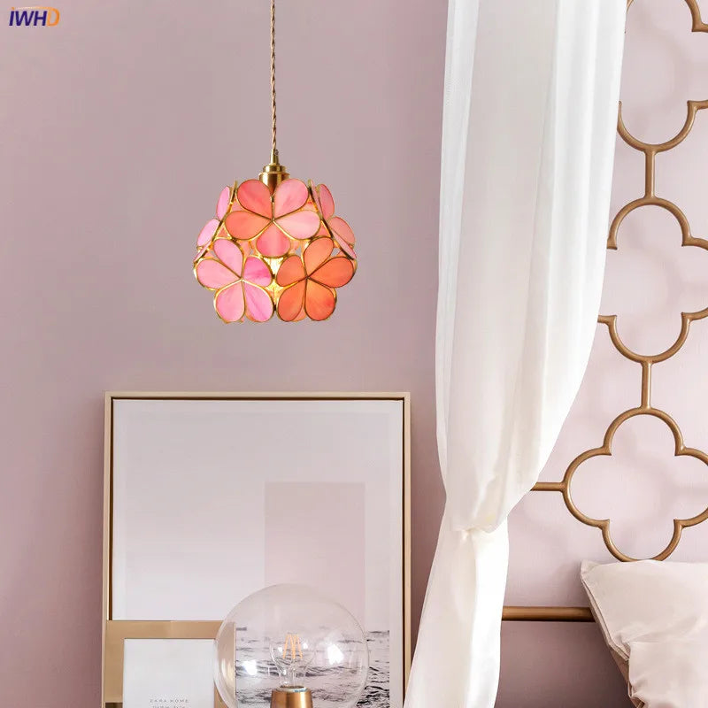 Pink floral pendant light hanging in a room with a mirror and decorative wall.