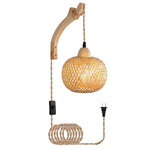 Woven rattan wall light fixture with wooden arm and coiled cable on a white background