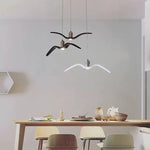 Minimalist bird wing chandelier above dining area