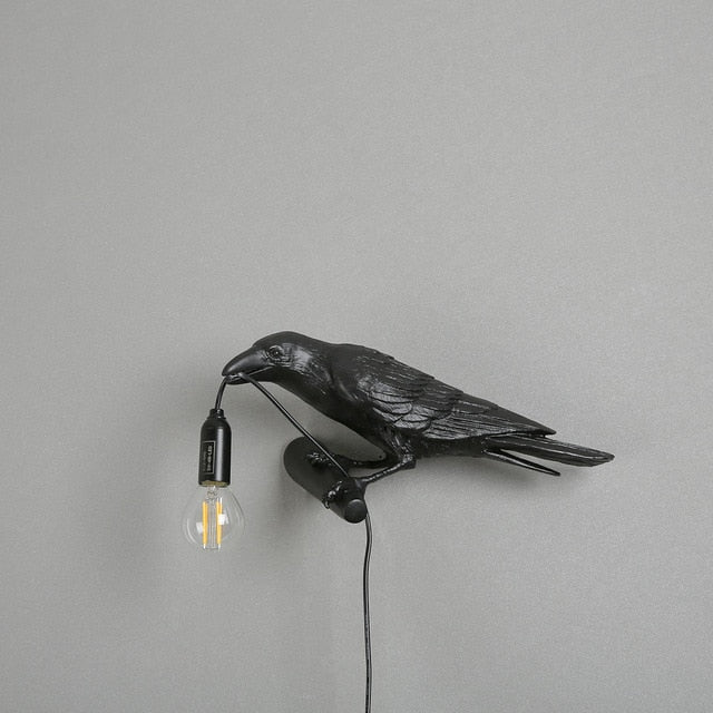 crow holding light bulb