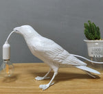 Crow-shaped lamp holding a LED bulb in its beak